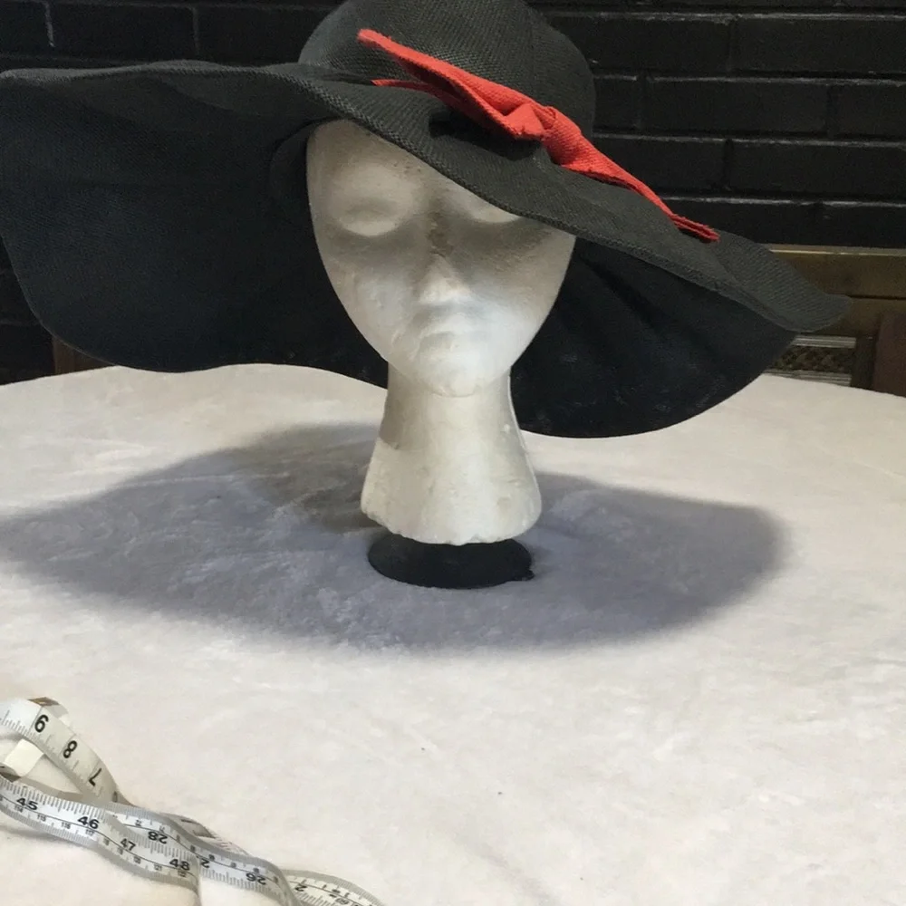 Woman’s black wide brim floppy burlap type hat with red bow.